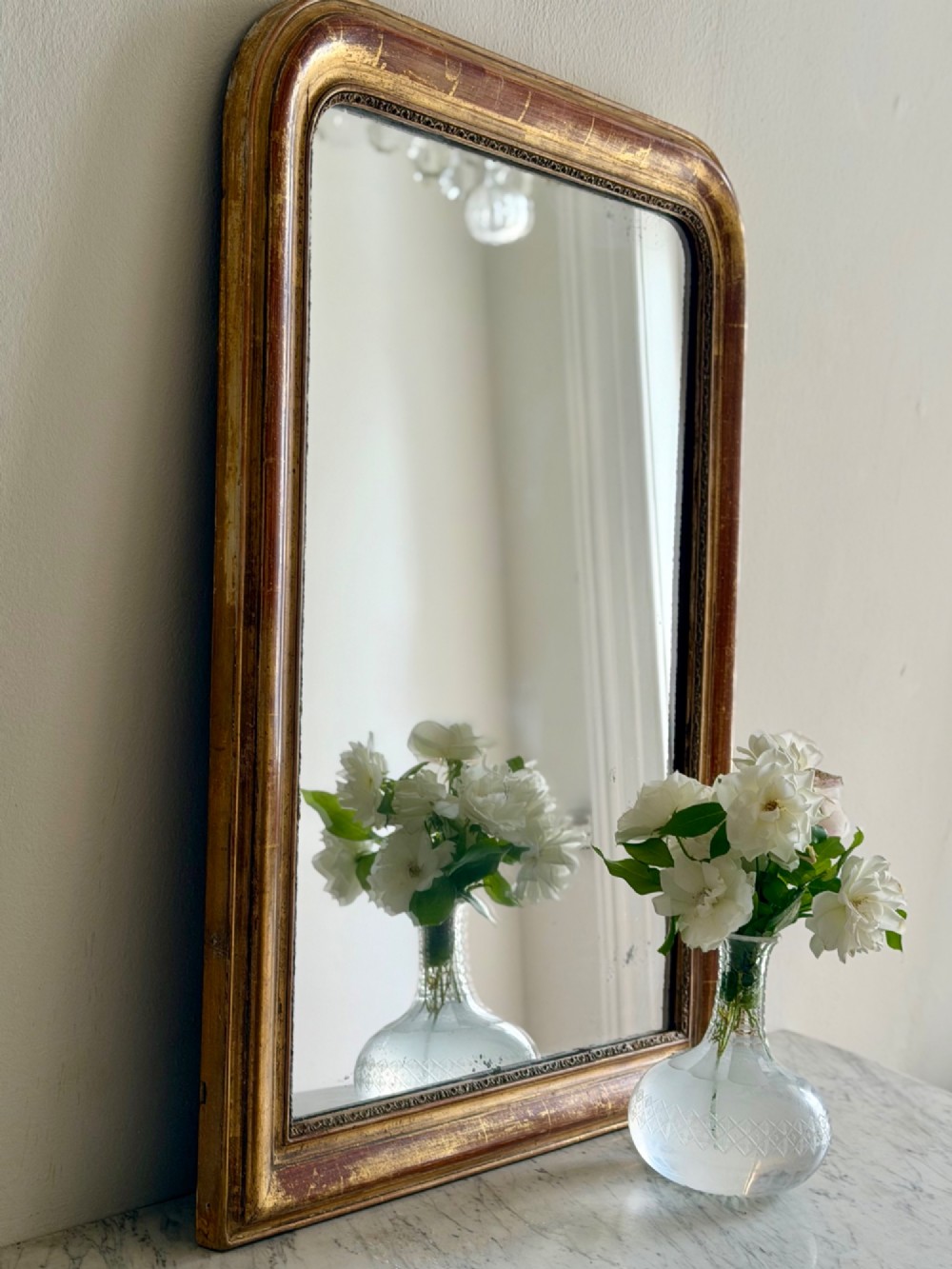 An antique French Louis Philippe wall mirror with a gold leaf gilded wooden frame featuring rounded upper corners and a beaded inner edge.