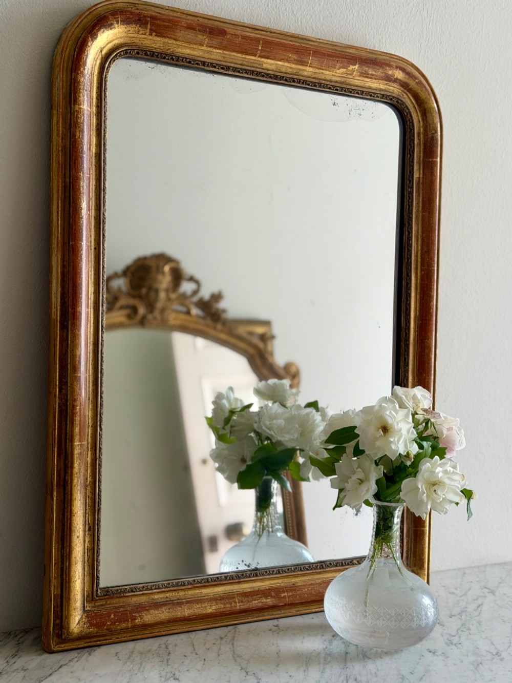 An antique French Louis Philippe wall mirror with a gold leaf gilded wooden frame featuring rounded upper corners and a beaded inner edge. View II