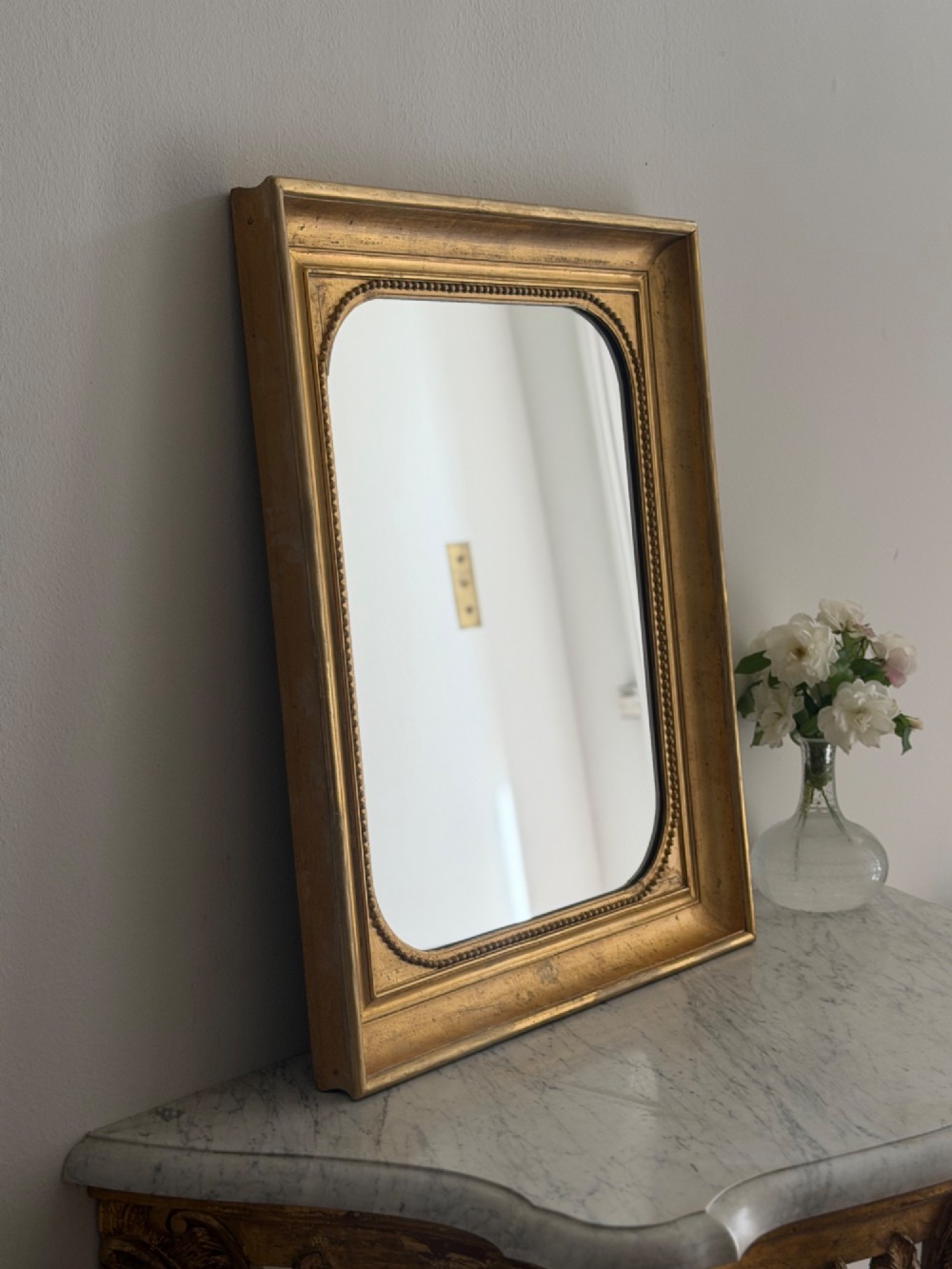A rectangular antique French wall mirror featuring a gilded wood frame with a beaded inner border. View II