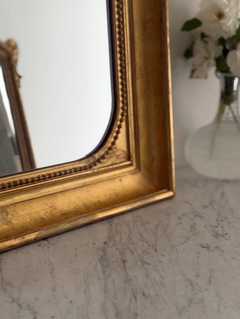 A rectangular antique French wall mirror featuring a gilded wood frame with a beaded inner border. View VIII
