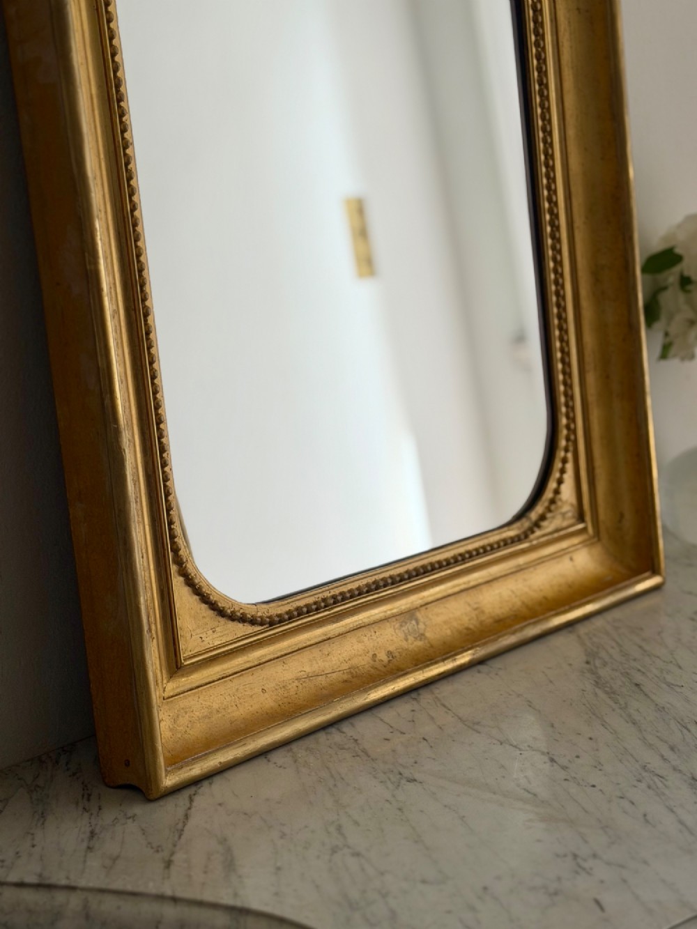 A rectangular antique French wall mirror featuring a gilded wood frame with a beaded inner border. View IX