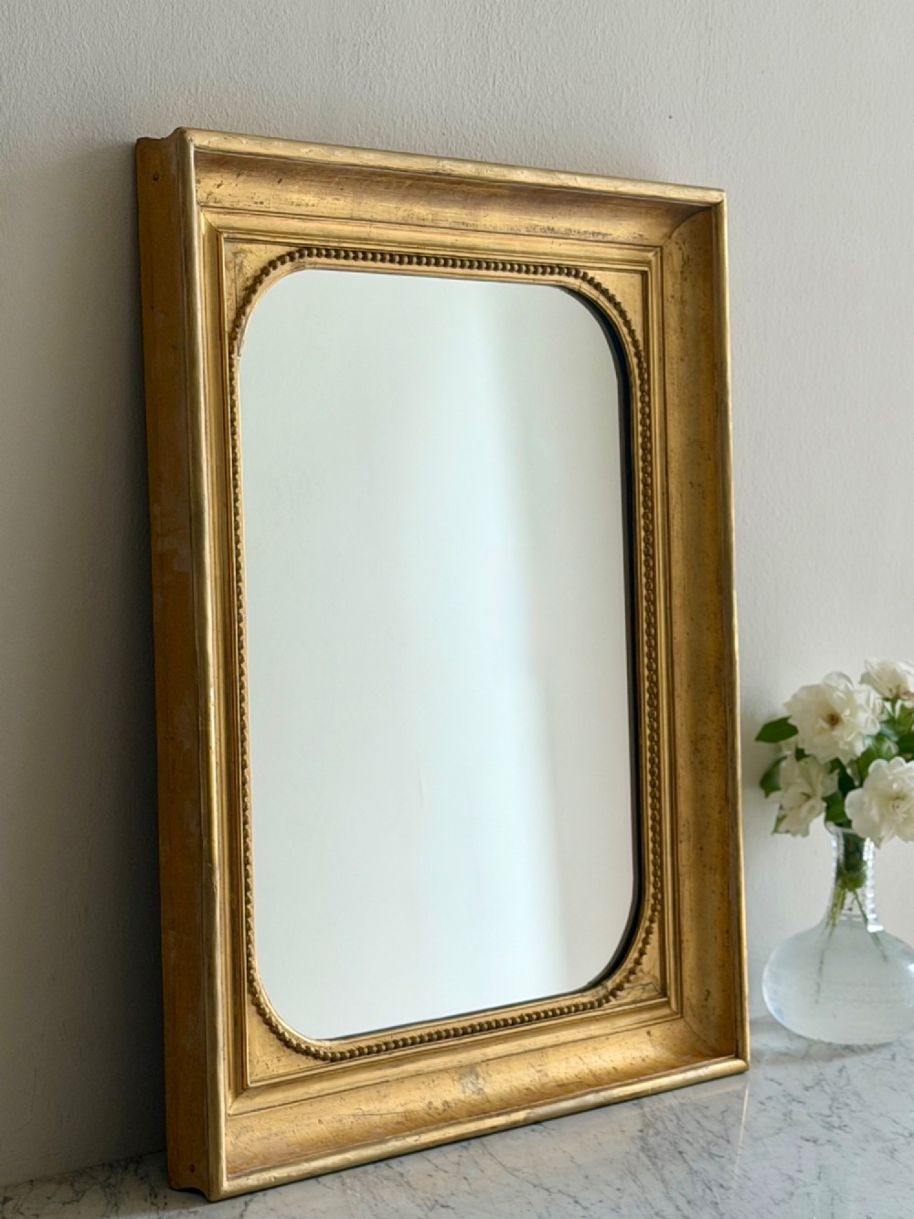 A rectangular antique French wall mirror featuring a gilded wood frame with a beaded inner border. View X