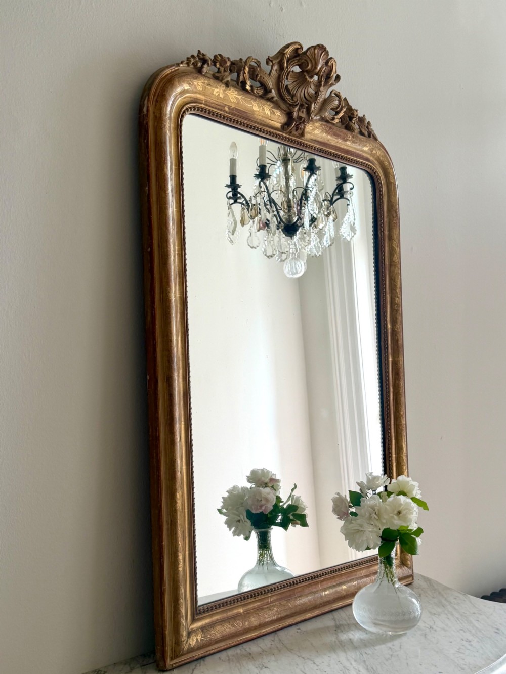 An antique French Louis Philippe giltwood mirror featuring a carved crest and incised floral frame detailing. View XIV