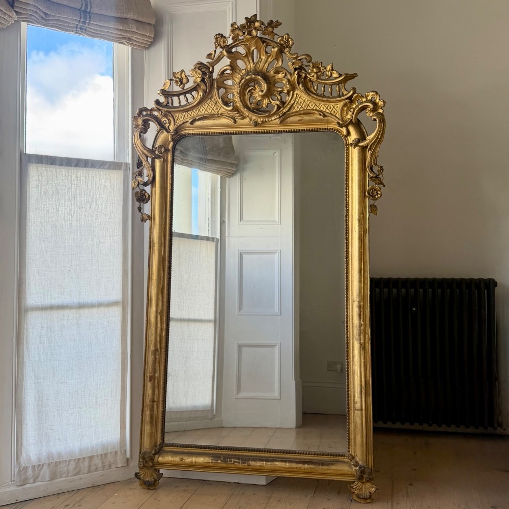 A large eighteenth-century French giltwood mirror featuring an ornate carved cresting with floral swags and a mercury glass plate. View III