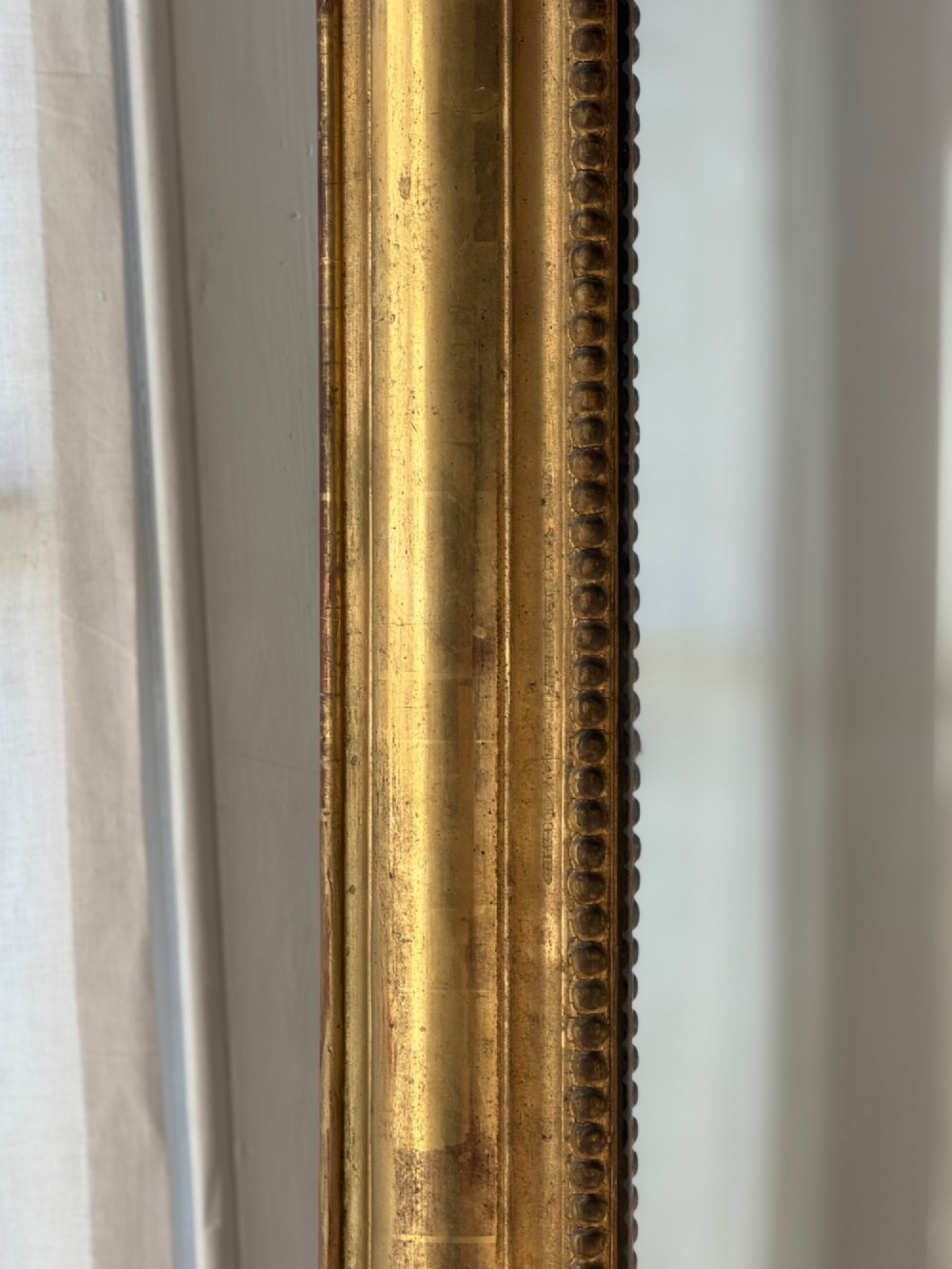 A large eighteenth-century French giltwood mirror featuring an ornate carved cresting with floral swags and a mercury glass plate. View VII