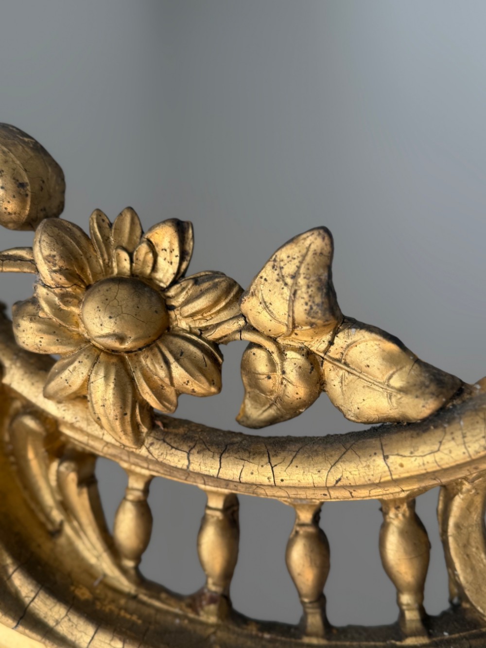 A large eighteenth-century French giltwood mirror featuring an ornate carved cresting with floral swags and a mercury glass plate. View XI