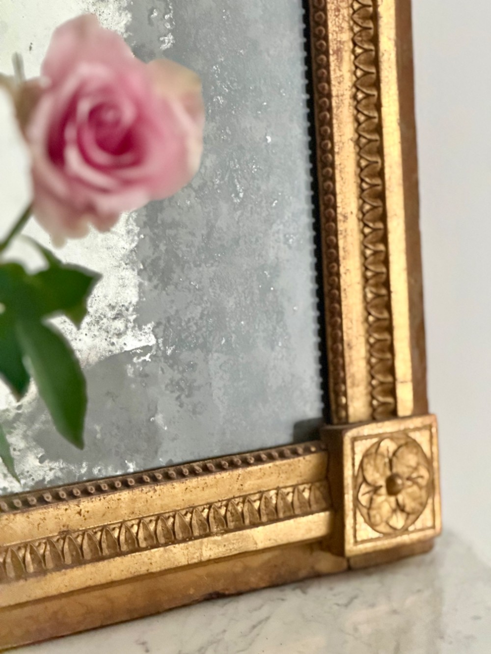 A rectangular 18th-century French giltwood mirror featuring heavy foxing on the glass plate and carved corner rosette details. View II