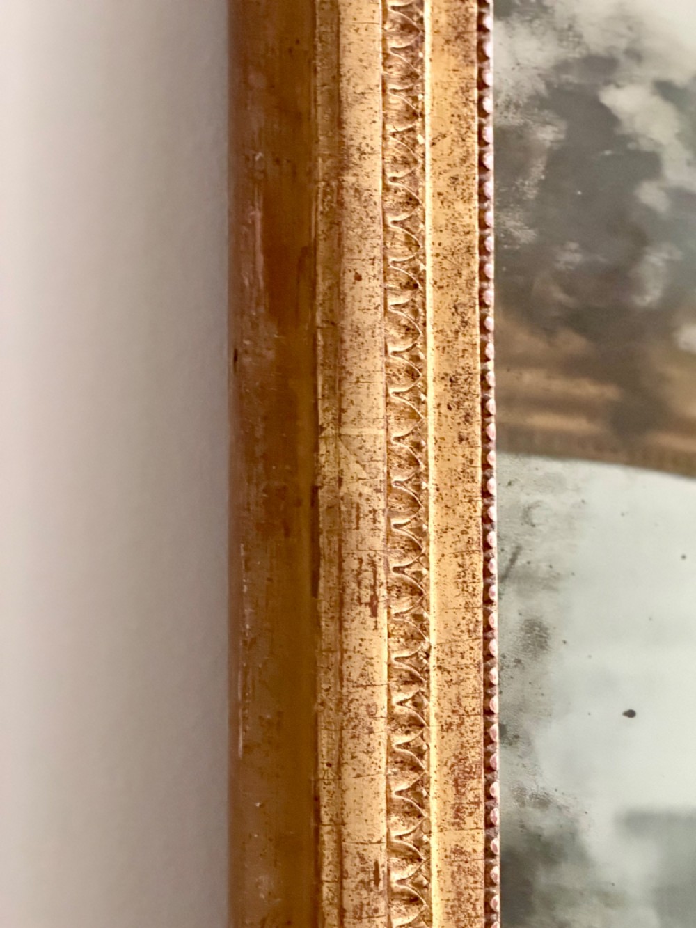 A rectangular 18th-century French giltwood mirror featuring heavy foxing on the glass plate and carved corner rosette details. View III