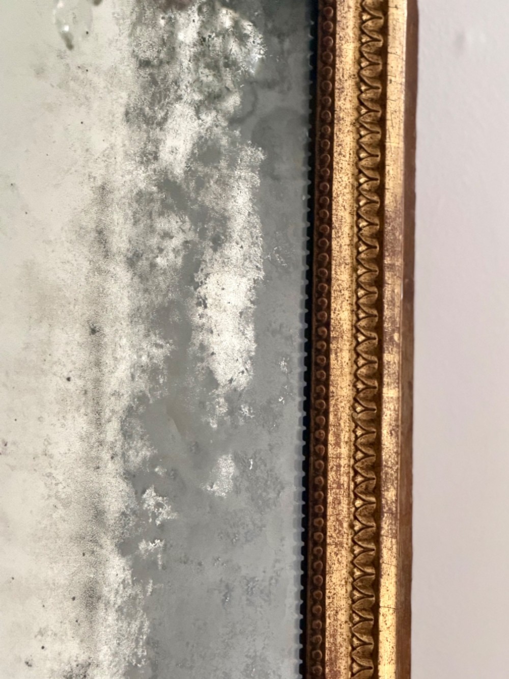 A rectangular 18th-century French giltwood mirror featuring heavy foxing on the glass plate and carved corner rosette details. View V