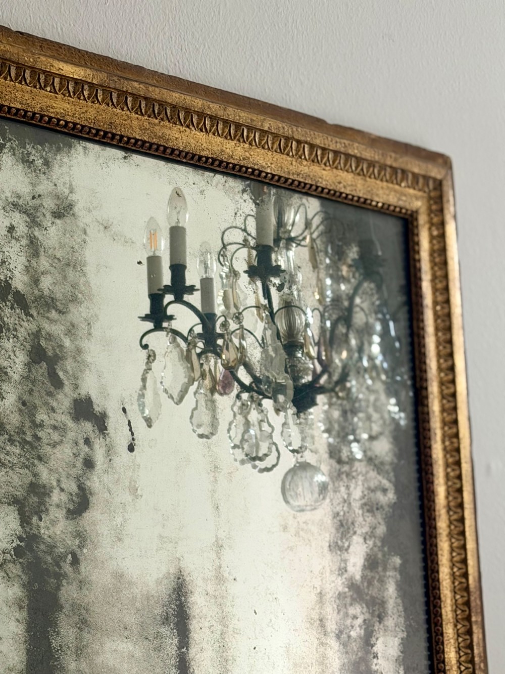 A rectangular 18th-century French giltwood mirror featuring heavy foxing on the glass plate and carved corner rosette details. View VI