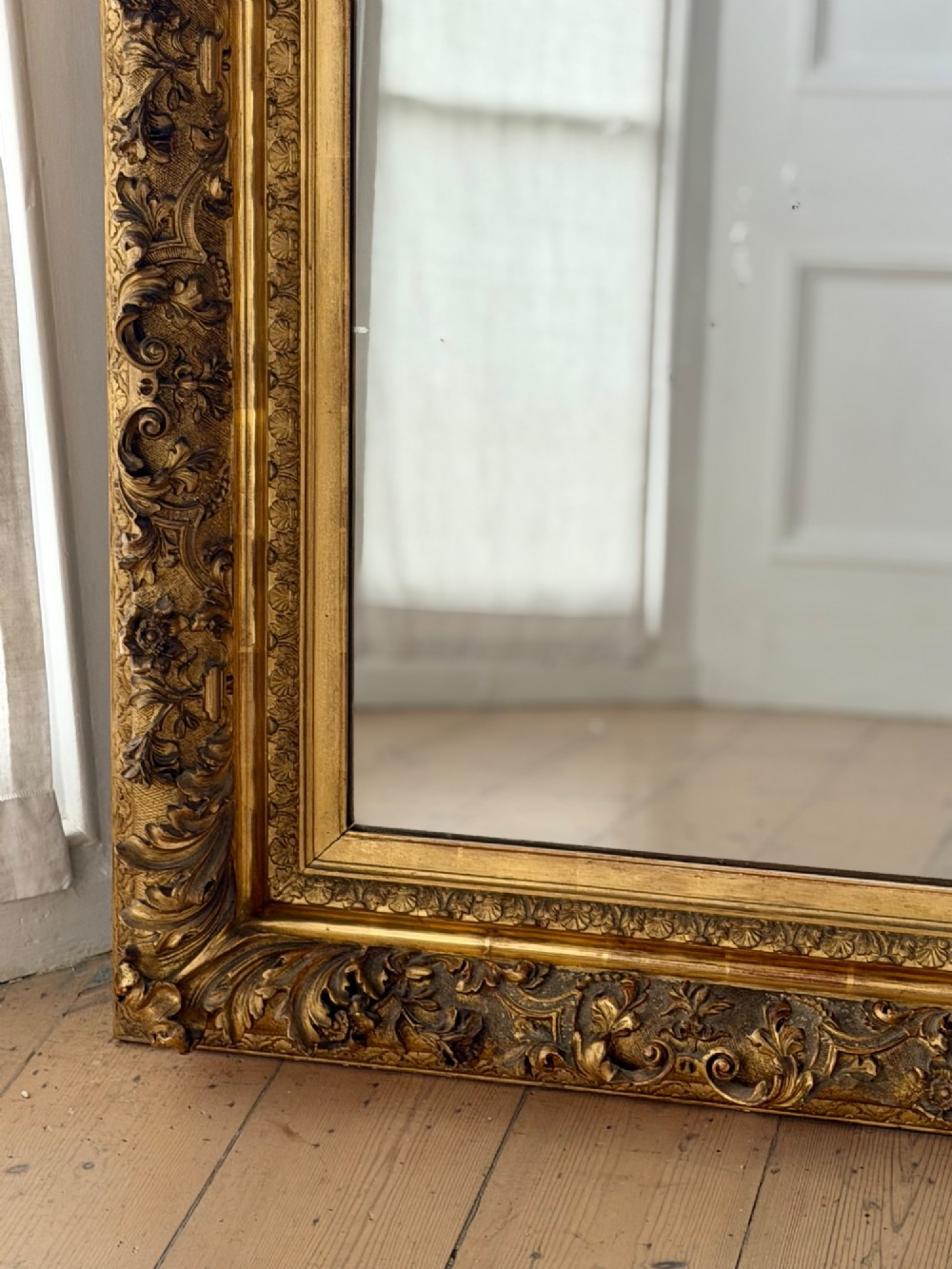 An antique rectangular French mirror featuring a carved giltwood frame with detailed leaf moulding and a mercury glass plate showing light foxing. View II