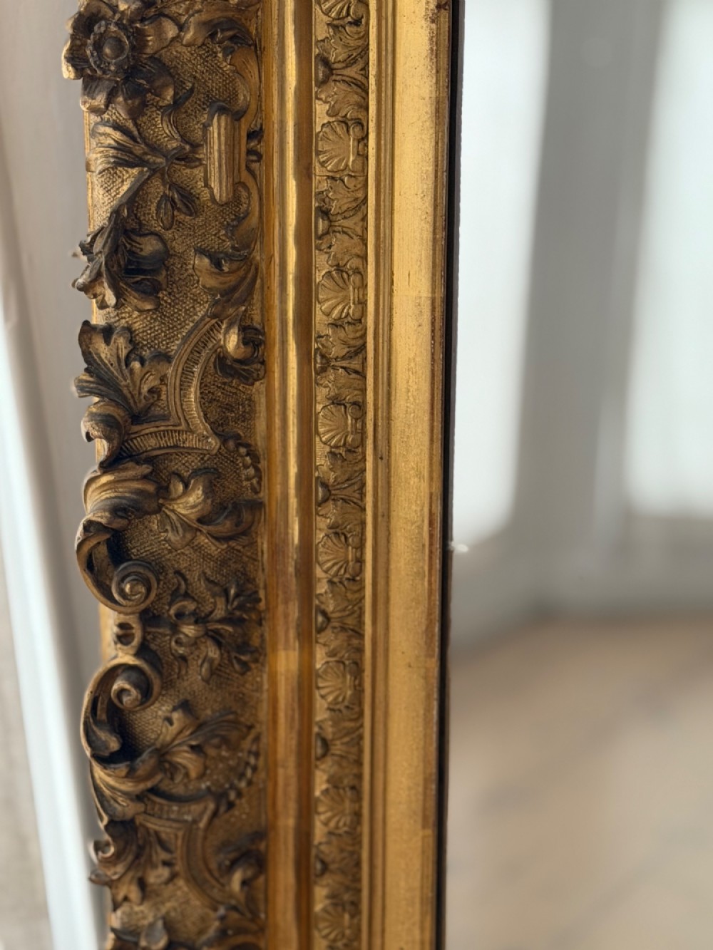 An antique rectangular French mirror featuring a carved giltwood frame with detailed leaf moulding and a mercury glass plate showing light foxing. View III