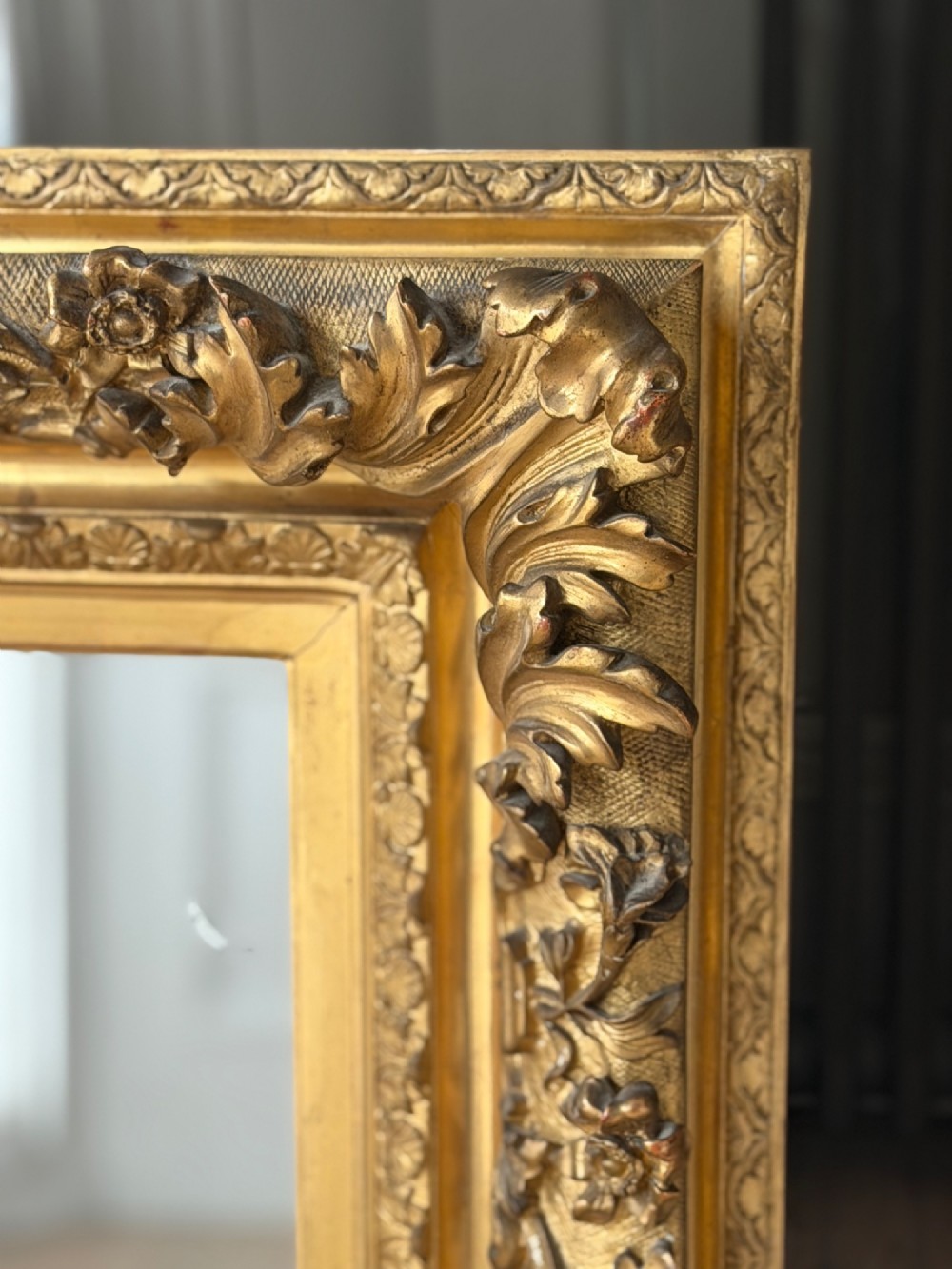 An antique rectangular French mirror featuring a carved giltwood frame with detailed leaf moulding and a mercury glass plate showing light foxing. View IV