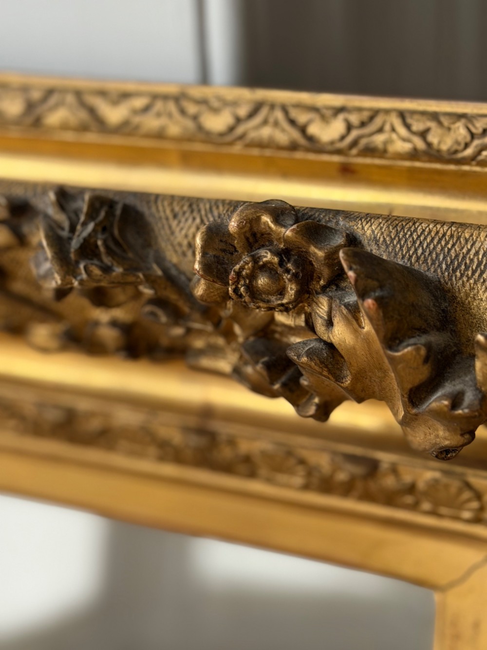 An antique rectangular French mirror featuring a carved giltwood frame with detailed leaf moulding and a mercury glass plate showing light foxing. View V