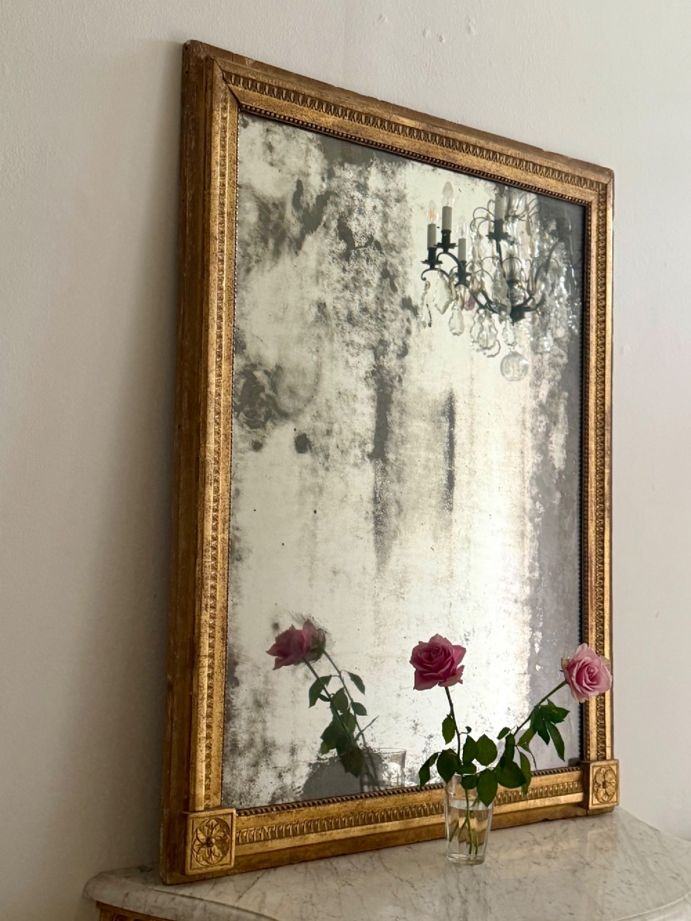 A rectangular 18th-century French giltwood mirror featuring heavy foxing on the glass plate and carved corner rosette details. View IX