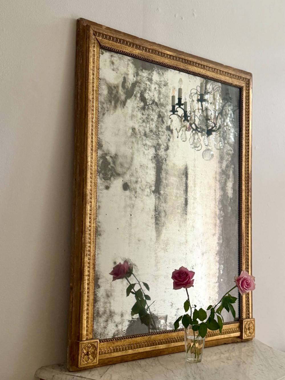 A rectangular 18th-century French giltwood mirror featuring heavy foxing on the glass plate and carved corner rosette details. View X