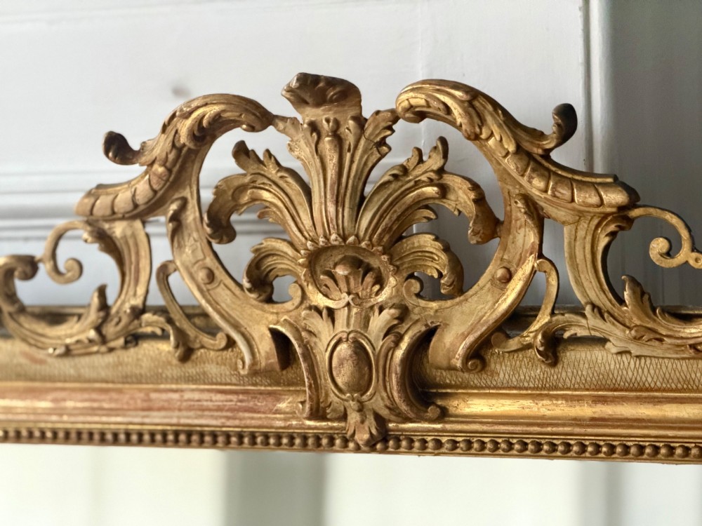 A tall French Louis Philippe mirror featuring a gold leaf frame with rounded upper shoulders, pearl bead moulding, and a decorative carved crest. View III