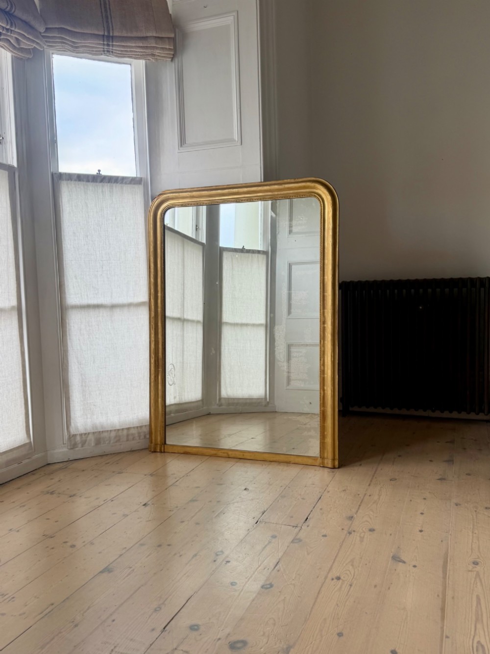 A large rectangular French Louis Philippe mirror featuring rounded top corners, a gilded frame with beaded inner moulding, and visible foxing on the glass plate. View II