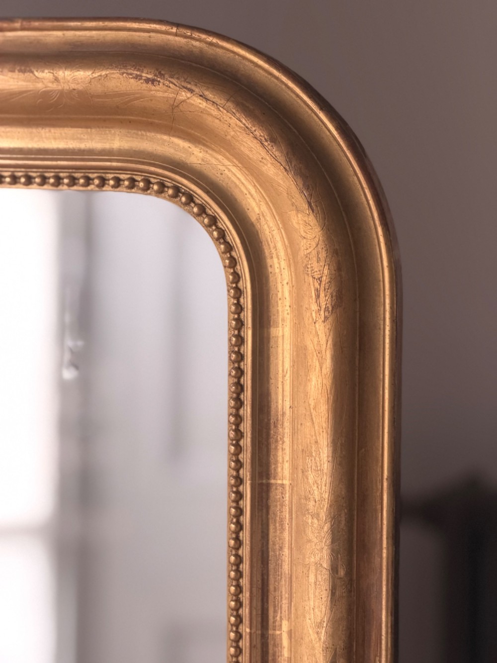 A large rectangular French Louis Philippe mirror featuring rounded top corners, a gilded frame with beaded inner moulding, and visible foxing on the glass plate. View III