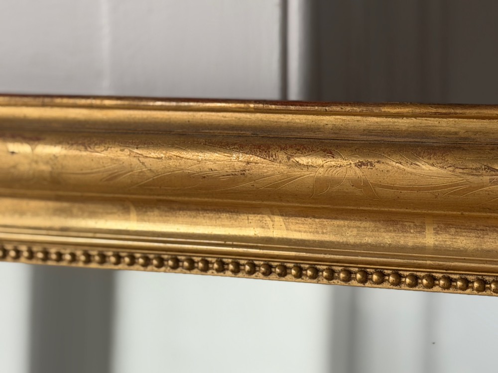 A large rectangular French Louis Philippe mirror featuring rounded top corners, a gilded frame with beaded inner moulding, and visible foxing on the glass plate. View IV