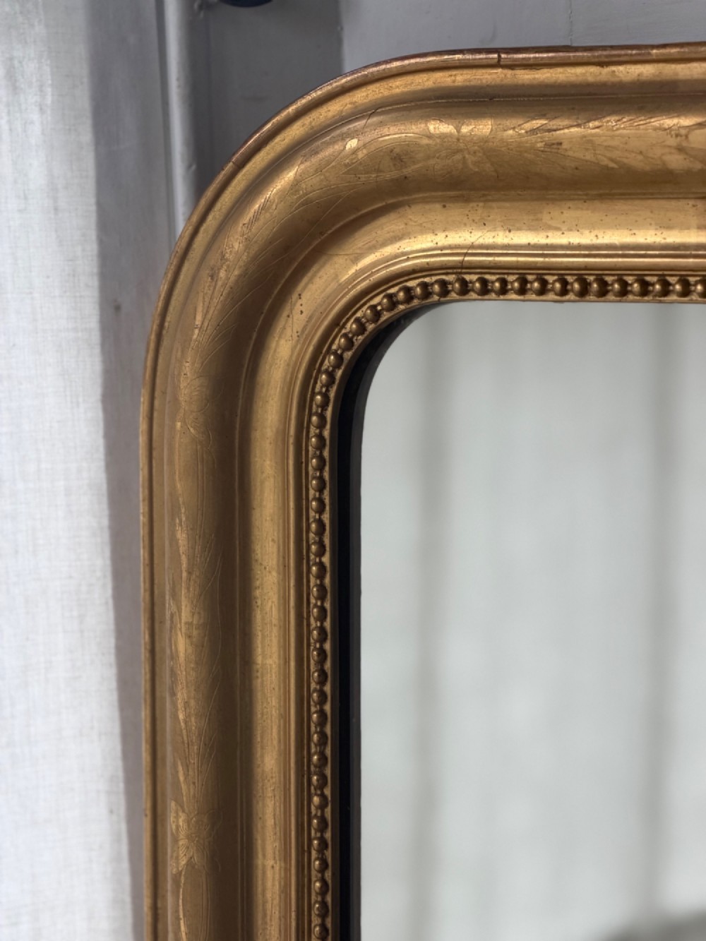 A large rectangular French Louis Philippe mirror featuring rounded top corners, a gilded frame with beaded inner moulding, and visible foxing on the glass plate. View V