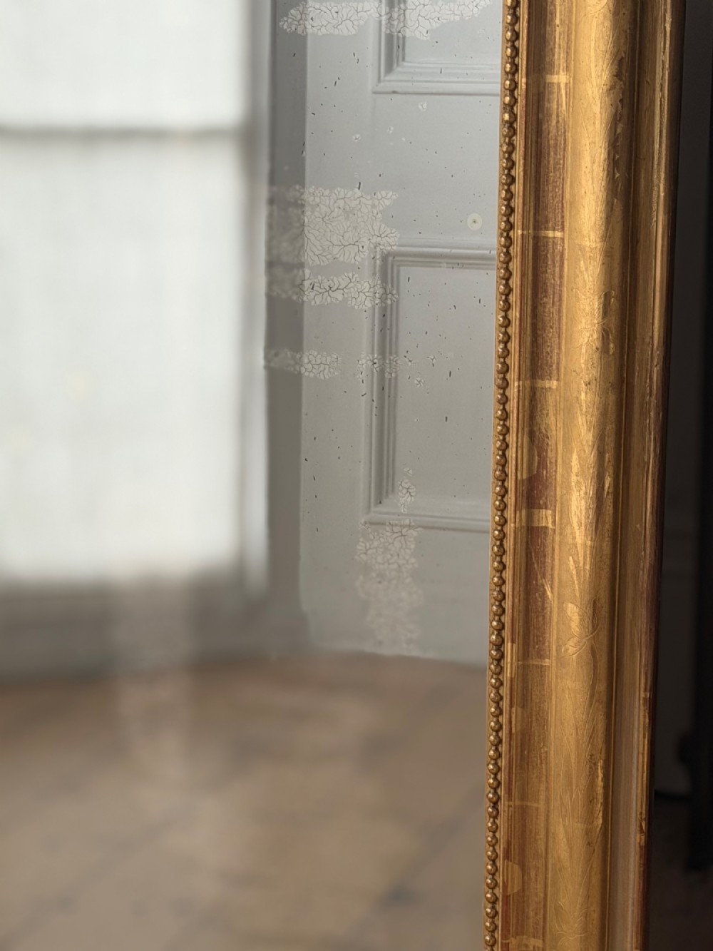 A large rectangular French Louis Philippe mirror featuring rounded top corners, a gilded frame with beaded inner moulding, and visible foxing on the glass plate. View VIII