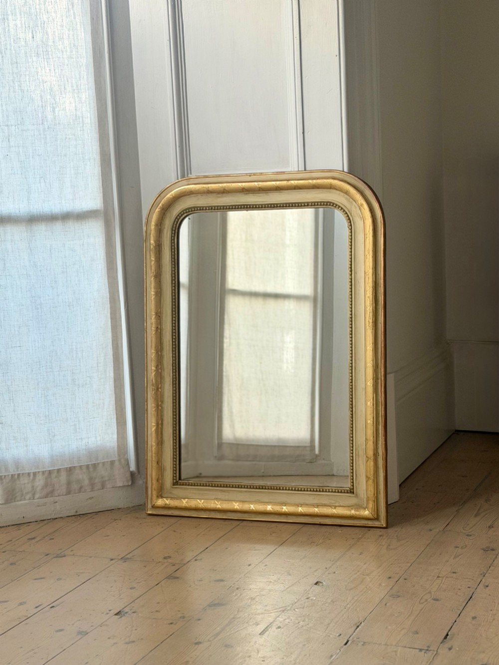 An antique Louis Philippe mirror with rounded upper corners, an incised crosshatch motif on the gilded frame, exposed white gesso, and a beaded inner border. View II