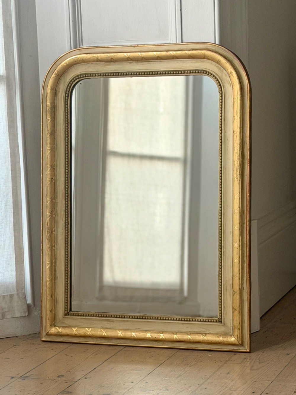 An antique Louis Philippe mirror with rounded upper corners, an incised crosshatch motif on the gilded frame, exposed white gesso, and a beaded inner border. View III
