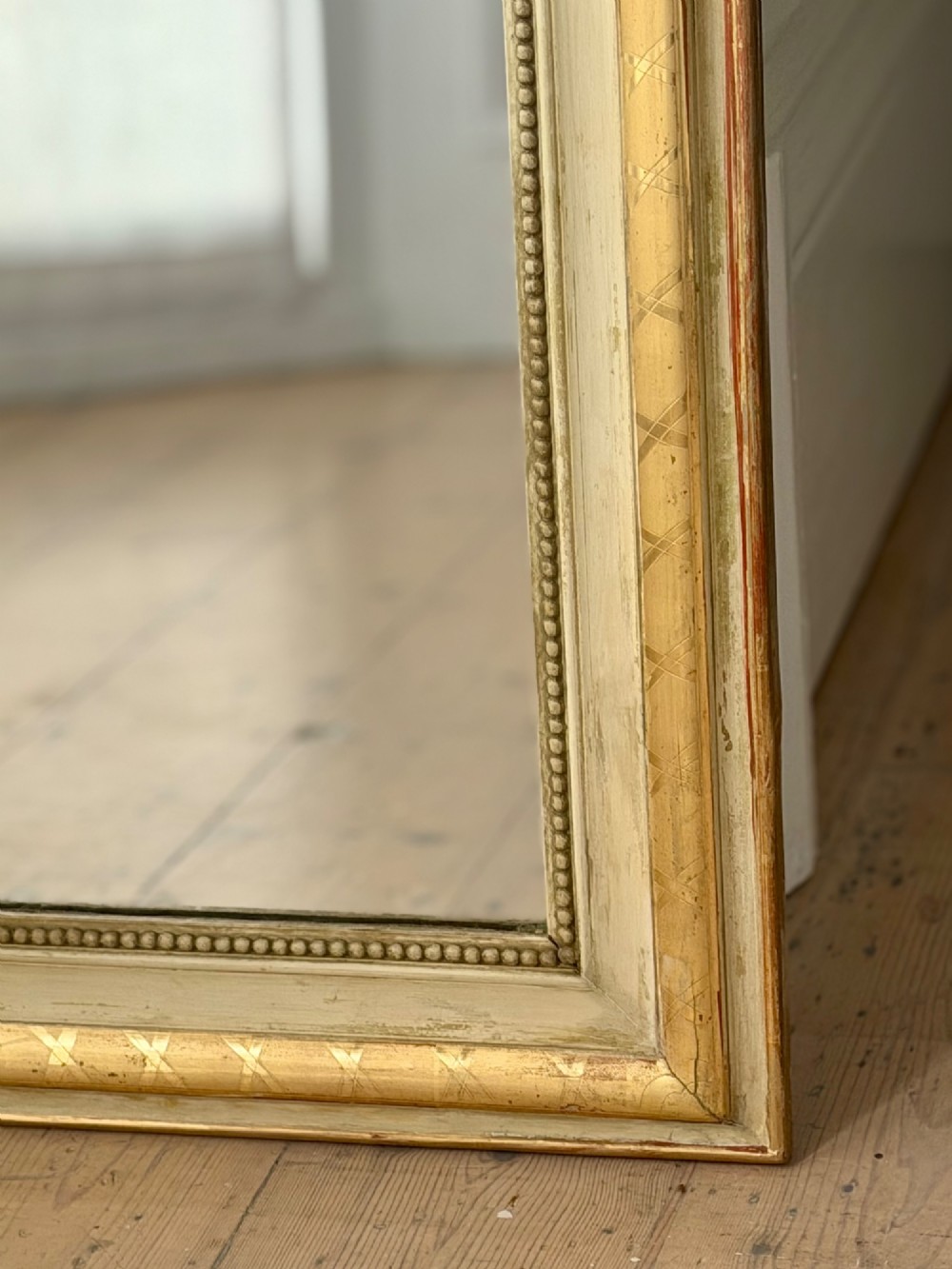 An antique Louis Philippe mirror with rounded upper corners, an incised crosshatch motif on the gilded frame, exposed white gesso, and a beaded inner border. View V