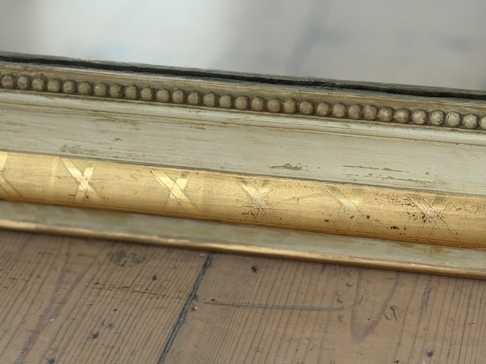 An antique Louis Philippe mirror with rounded upper corners, an incised crosshatch motif on the gilded frame, exposed white gesso, and a beaded inner border. View VII