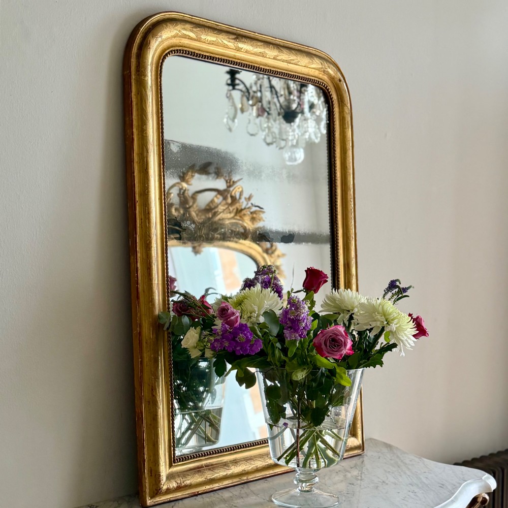 A rectangular antique French gilt mirror featuring rounded upper corners, an engraved gold leaf frame with beaded inner moulding, and foxed mercury glass. View II