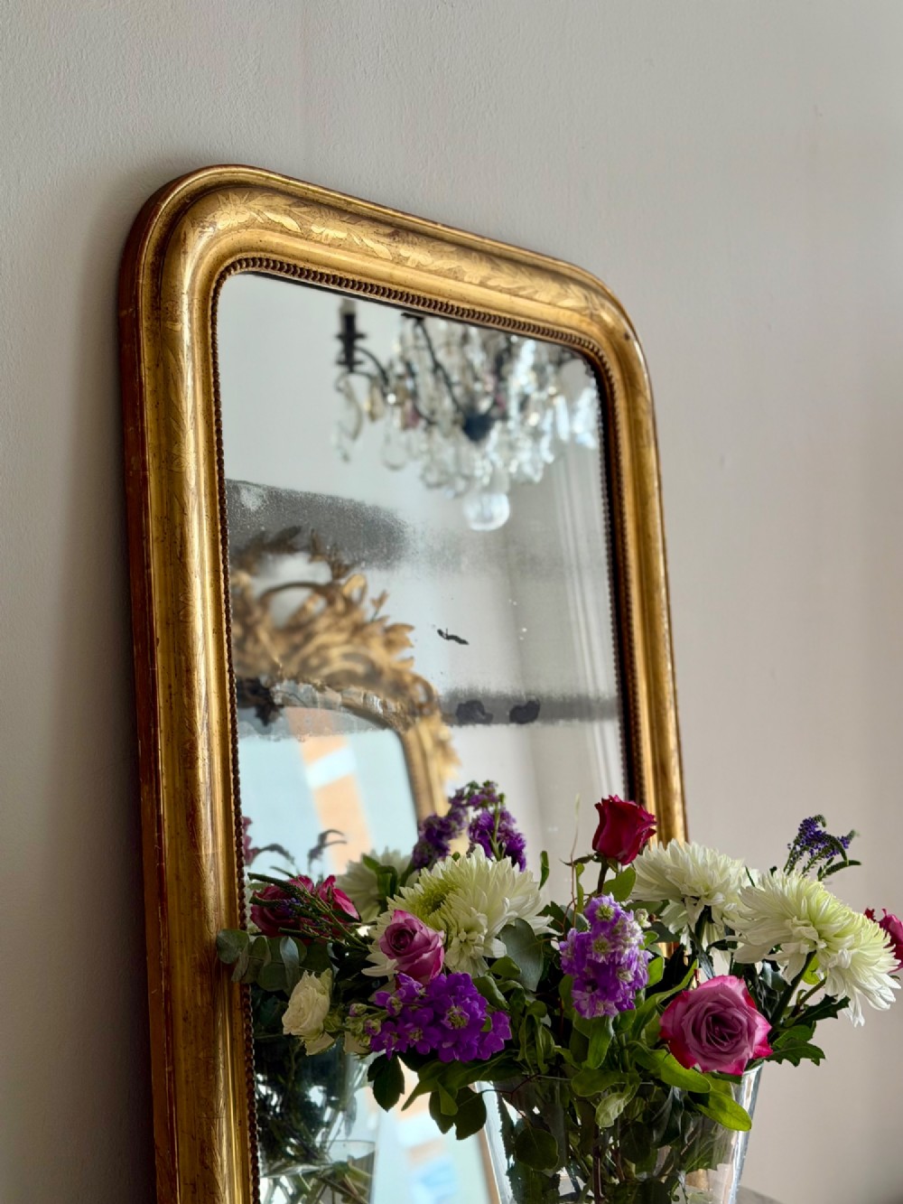A rectangular antique French gilt mirror featuring rounded upper corners, an engraved gold leaf frame with beaded inner moulding, and foxed mercury glass. View III