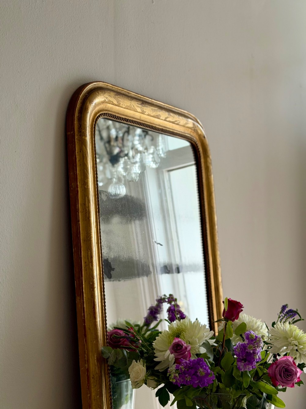 A rectangular antique French gilt mirror featuring rounded upper corners, an engraved gold leaf frame with beaded inner moulding, and foxed mercury glass. View IV