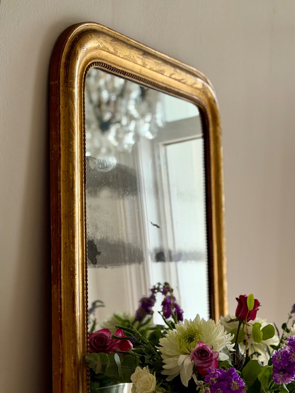 A rectangular antique French gilt mirror featuring rounded upper corners, an engraved gold leaf frame with beaded inner moulding, and foxed mercury glass. View VI