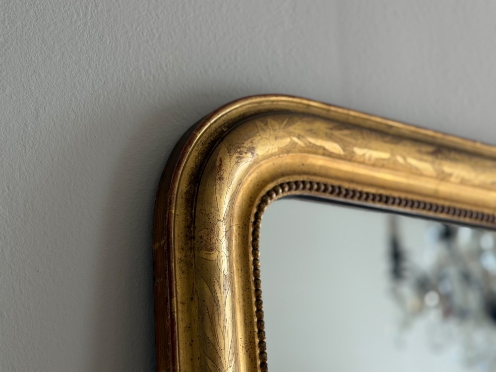A rectangular antique French gilt mirror featuring rounded upper corners, an engraved gold leaf frame with beaded inner moulding, and foxed mercury glass. View VIII