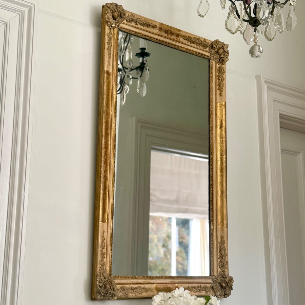 A tall rectangular nineteenth-century French Napoleon III mirror with a gilded and bare gesso frame featuring floral corner mouldings and a mercury glass plate. View II
