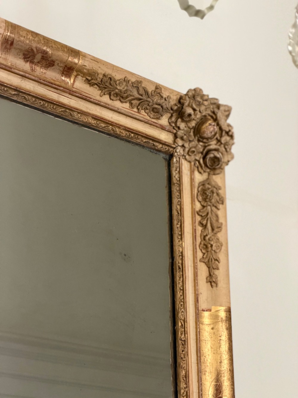 A tall rectangular nineteenth-century French Napoleon III mirror with a gilded and bare gesso frame featuring floral corner mouldings and a mercury glass plate. View III