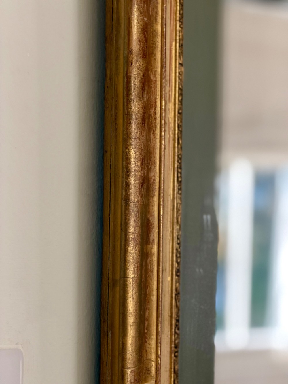 A tall rectangular nineteenth-century French Napoleon III mirror with a gilded and bare gesso frame featuring floral corner mouldings and a mercury glass plate. View IV
