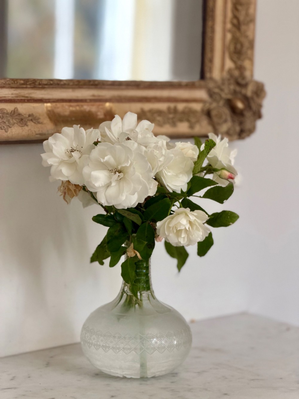 A tall rectangular nineteenth-century French Napoleon III mirror with a gilded and bare gesso frame featuring floral corner mouldings and a mercury glass plate. View V