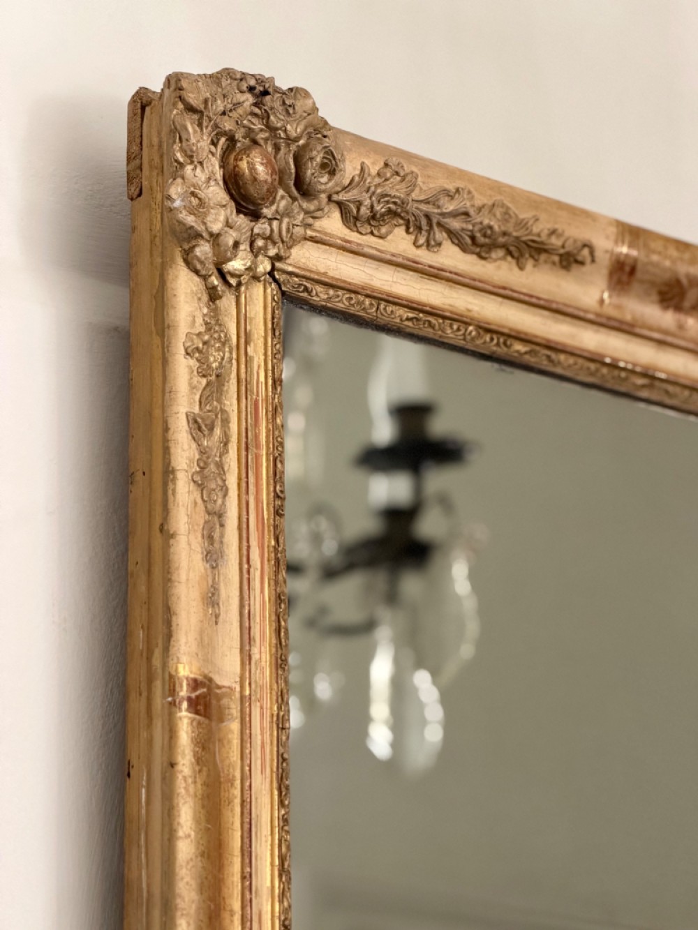 A tall rectangular nineteenth-century French Napoleon III mirror with a gilded and bare gesso frame featuring floral corner mouldings and a mercury glass plate. View VI