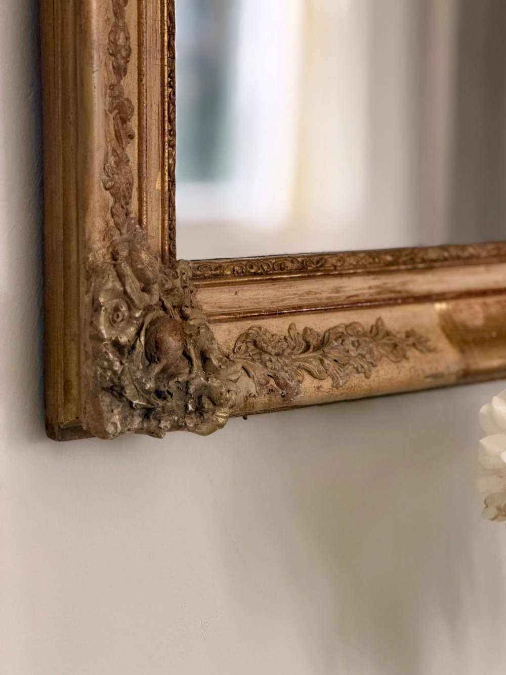A tall rectangular nineteenth-century French Napoleon III mirror with a gilded and bare gesso frame featuring floral corner mouldings and a mercury glass plate. View VIII