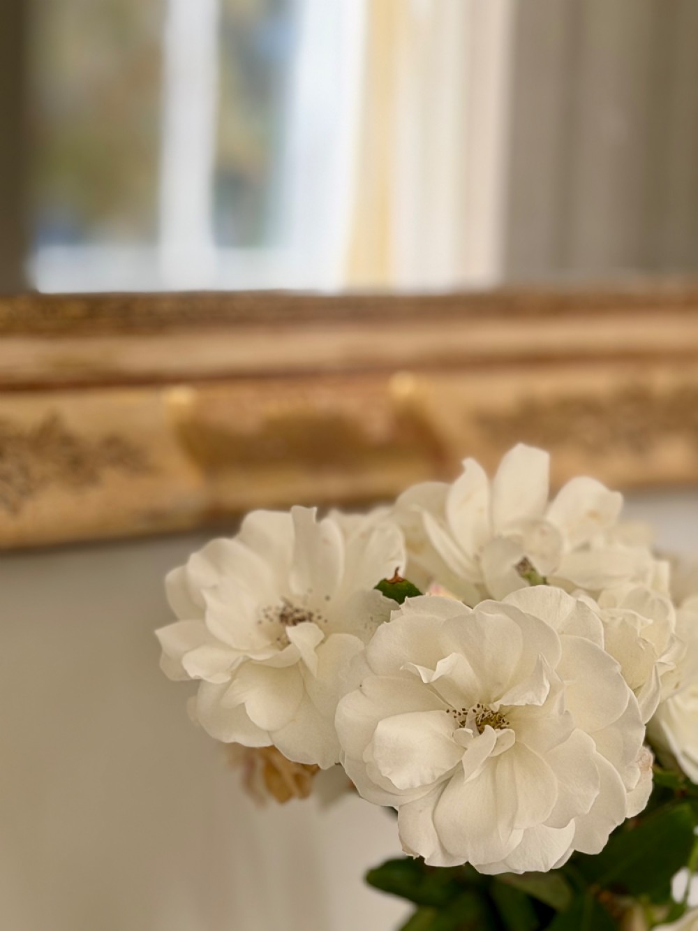 A tall rectangular nineteenth-century French Napoleon III mirror with a gilded and bare gesso frame featuring floral corner mouldings and a mercury glass plate. View IX