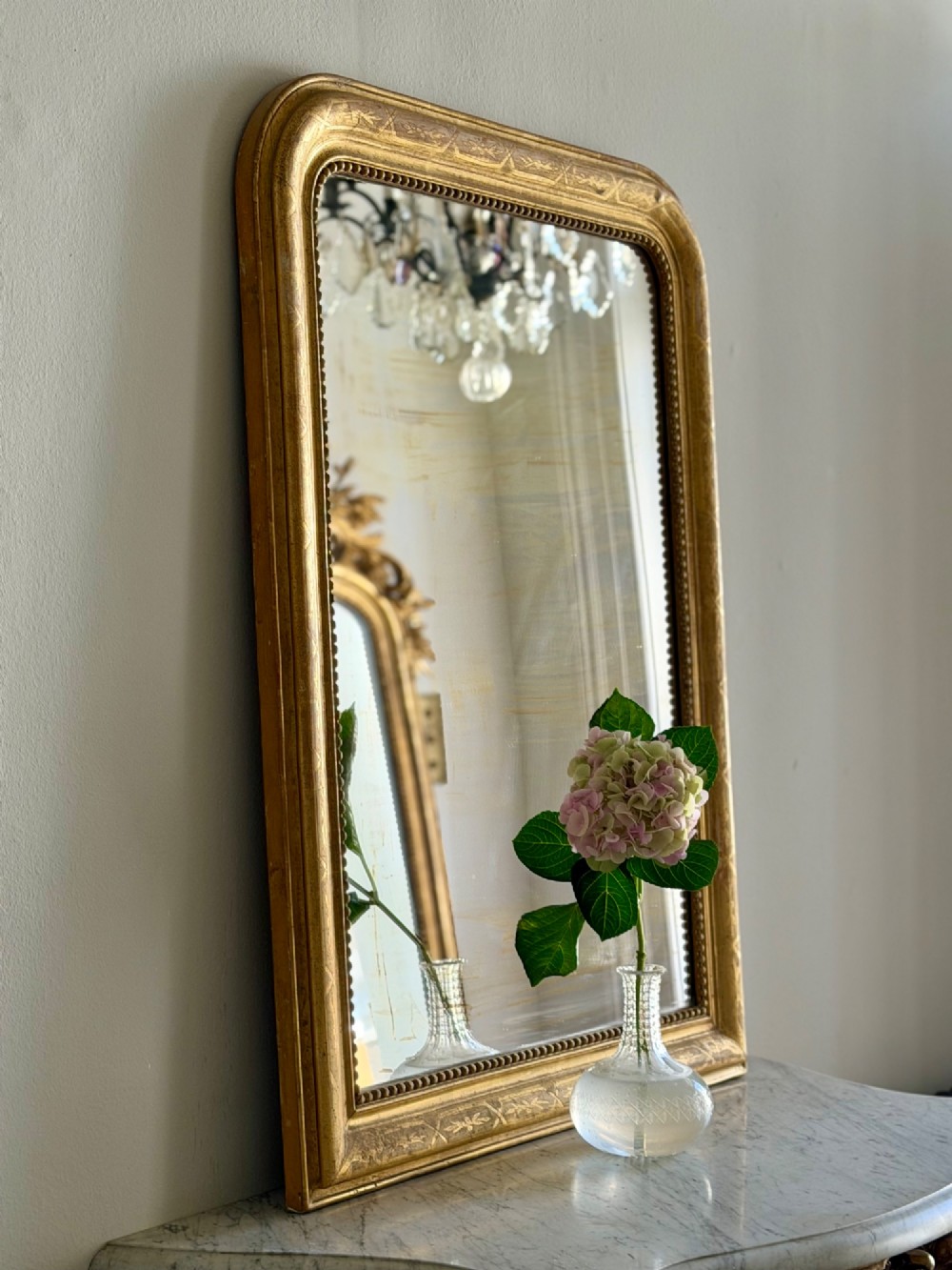 A rectangular 19th-century Louis Philippe mirror featuring rounded upper corners, an engraved gold leaf frame, beaded interior trim, and aged mirror glass. View II