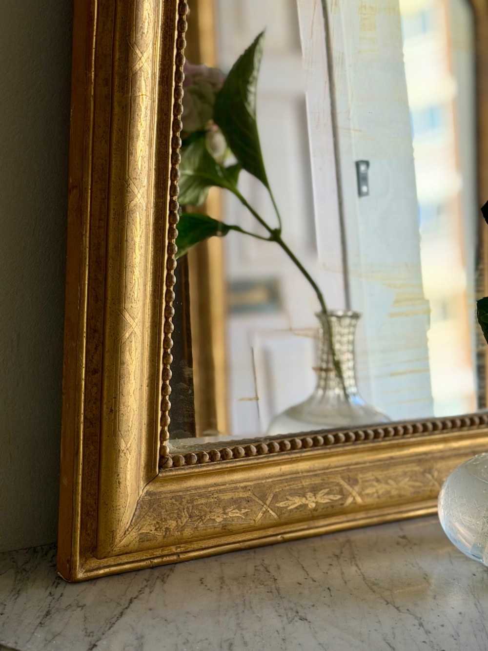 A rectangular 19th-century Louis Philippe mirror featuring rounded upper corners, an engraved gold leaf frame, beaded interior trim, and aged mirror glass. View IV