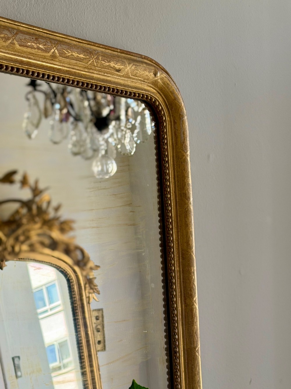 A rectangular 19th-century Louis Philippe mirror featuring rounded upper corners, an engraved gold leaf frame, beaded interior trim, and aged mirror glass. View VI