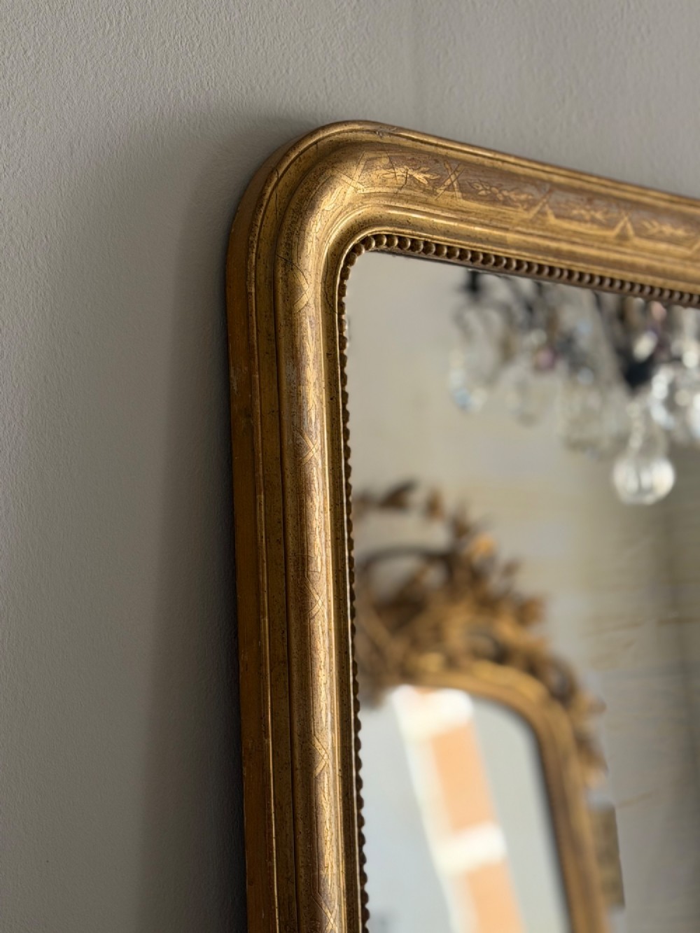 A rectangular 19th-century Louis Philippe mirror featuring rounded upper corners, an engraved gold leaf frame, beaded interior trim, and aged mirror glass. View VII
