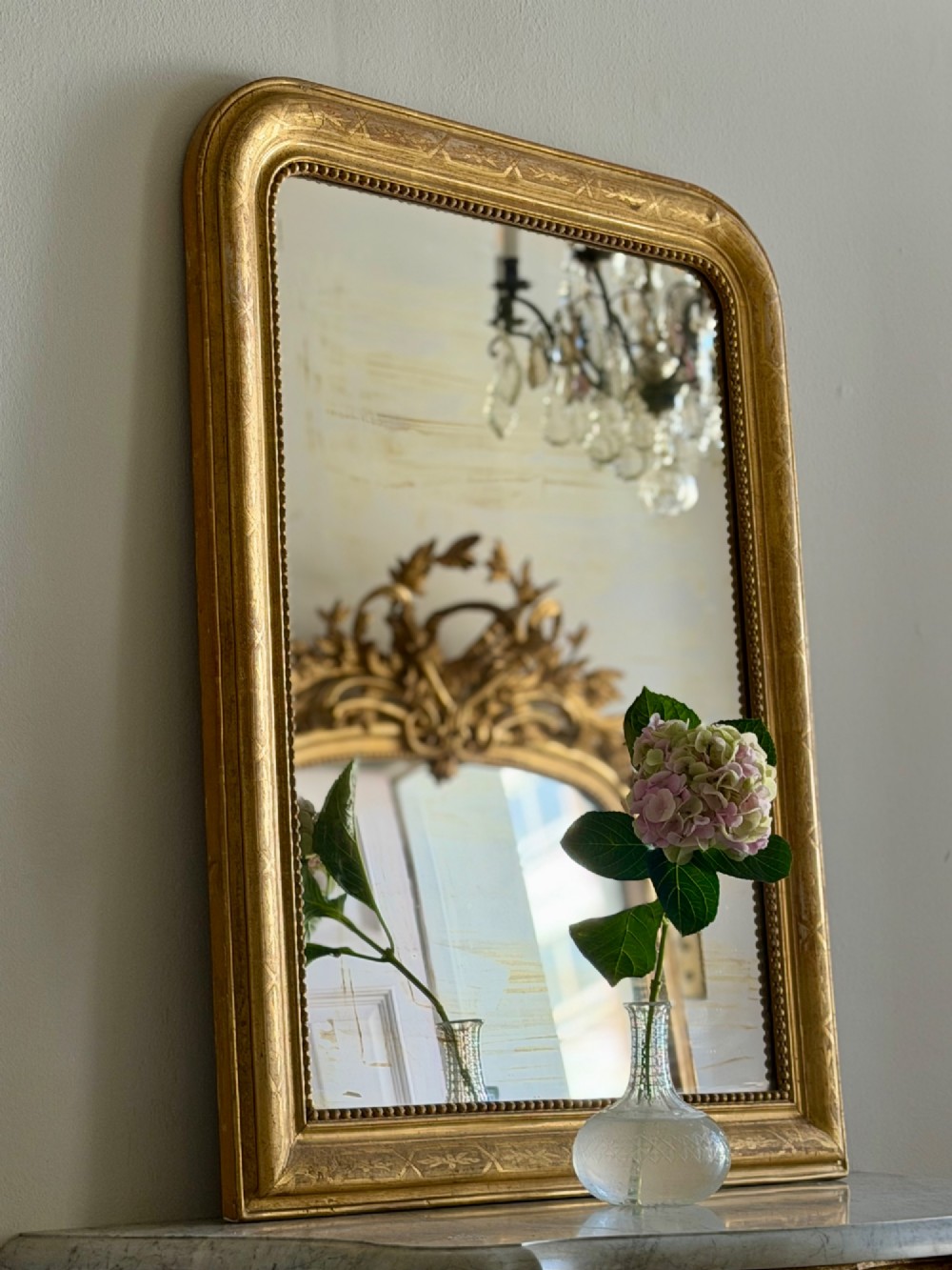 A rectangular 19th-century Louis Philippe mirror featuring rounded upper corners, an engraved gold leaf frame, beaded interior trim, and aged mirror glass. View VIII