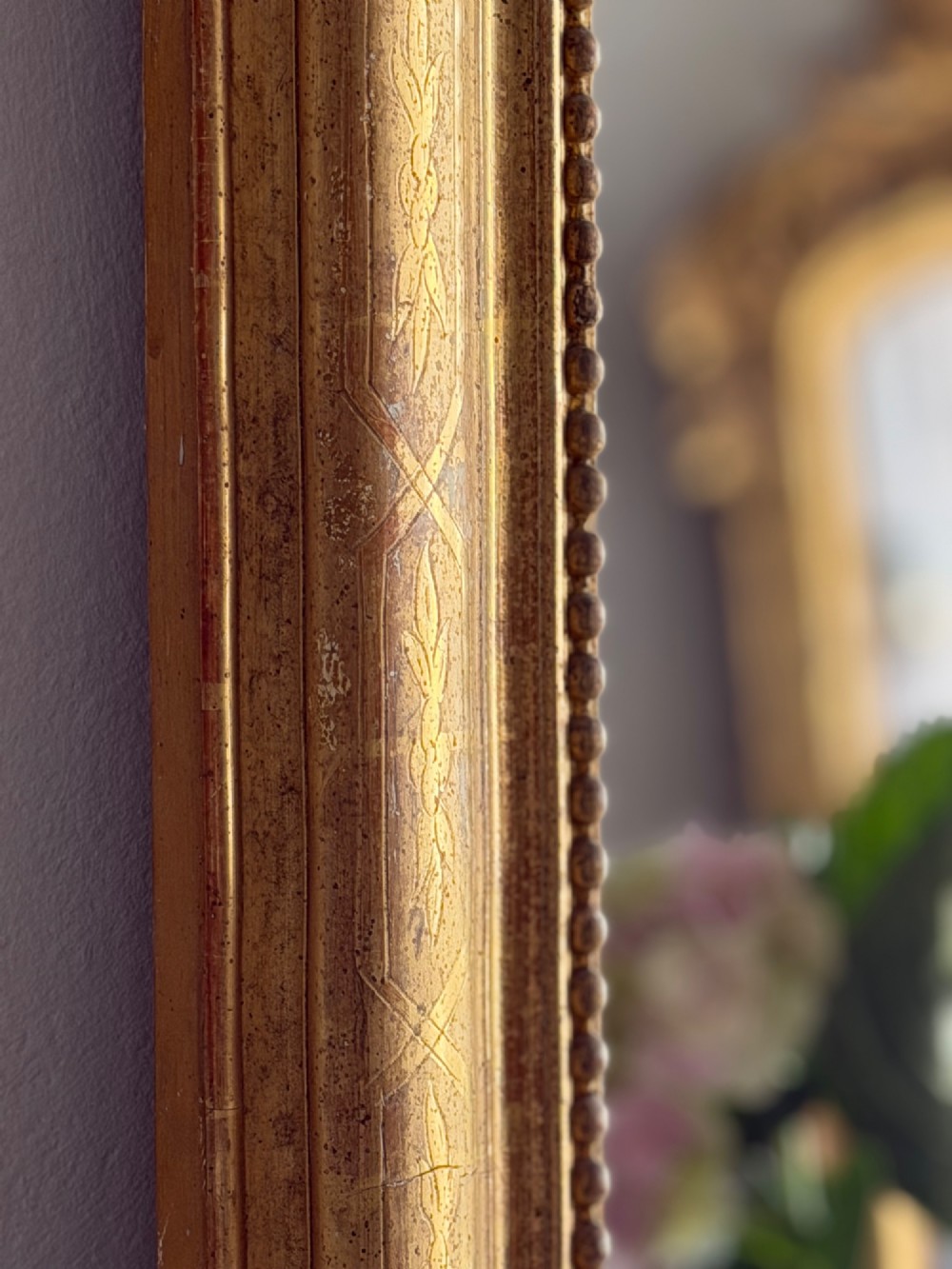 A rectangular 19th-century Louis Philippe mirror featuring rounded upper corners, an engraved gold leaf frame, beaded interior trim, and aged mirror glass. View X