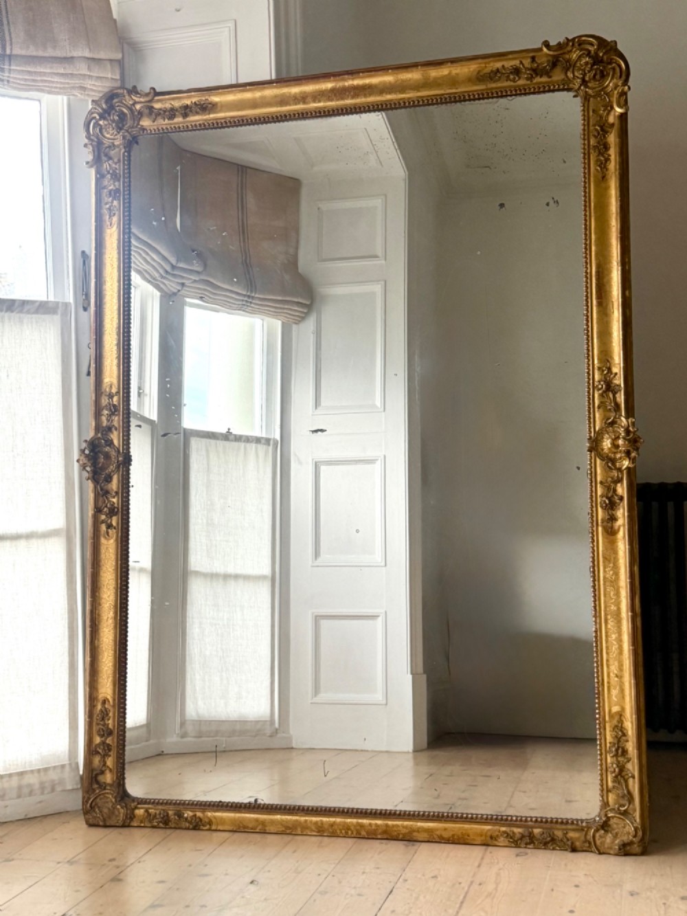 A large rectangular French Napoleon III giltwood leaner mirror featuring ornate carved foliate mouldings and an aged glass plate. View II