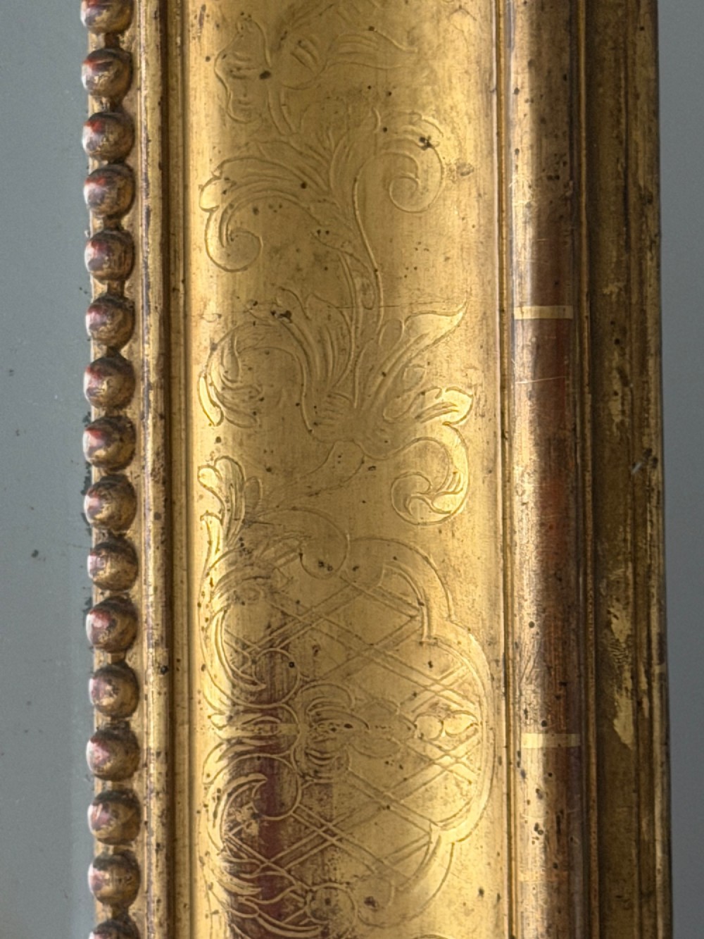 A large rectangular French Napoleon III giltwood leaner mirror featuring ornate carved foliate mouldings and an aged glass plate. View IV